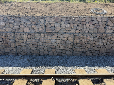 July 11th 2025: close up of the gabion wall with new full length drain to the bottom and topsoil above. The temporary transhipment siding is shown which will be relaid.
